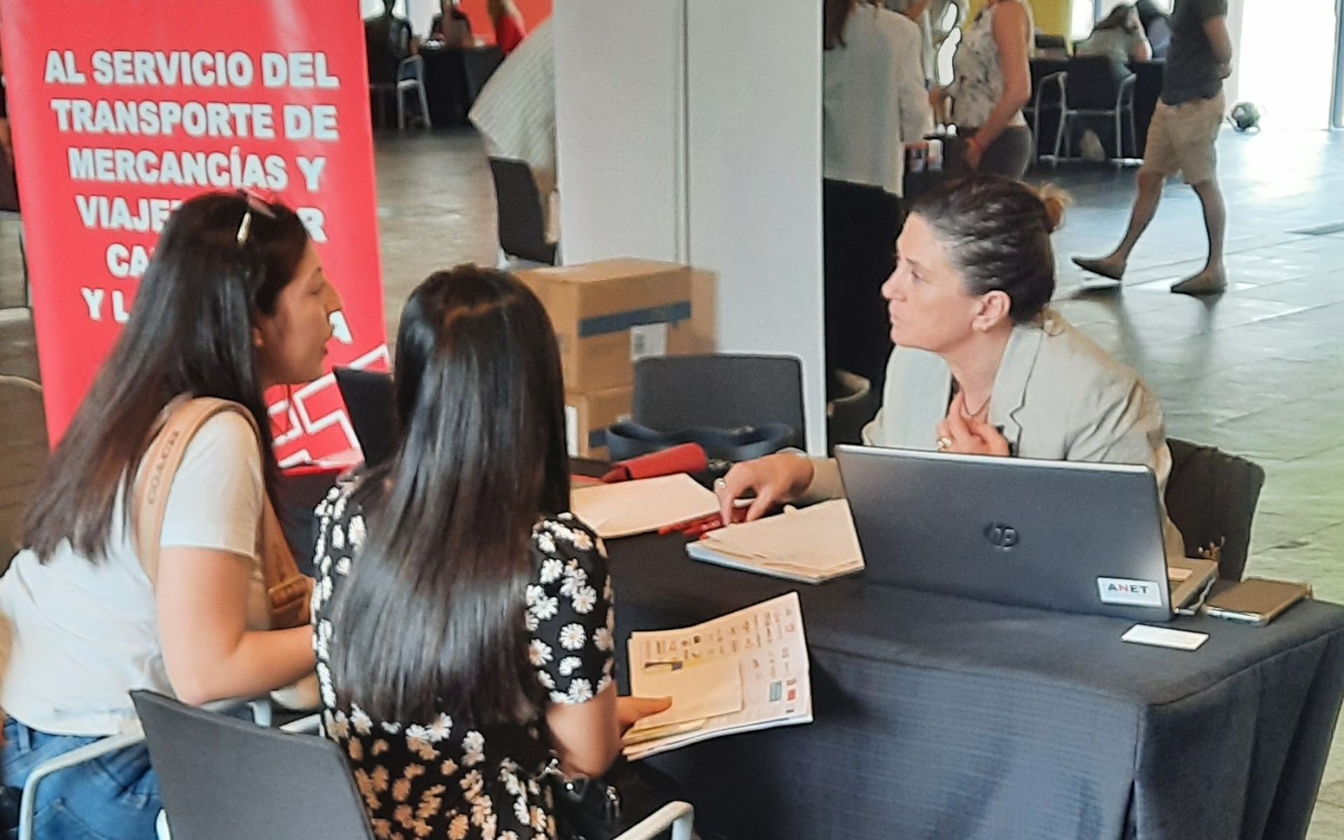 Natalia Aguirre, responsable de Formación de ANET, atendiendo a dos jóvenes en el NavarraJobs 2023