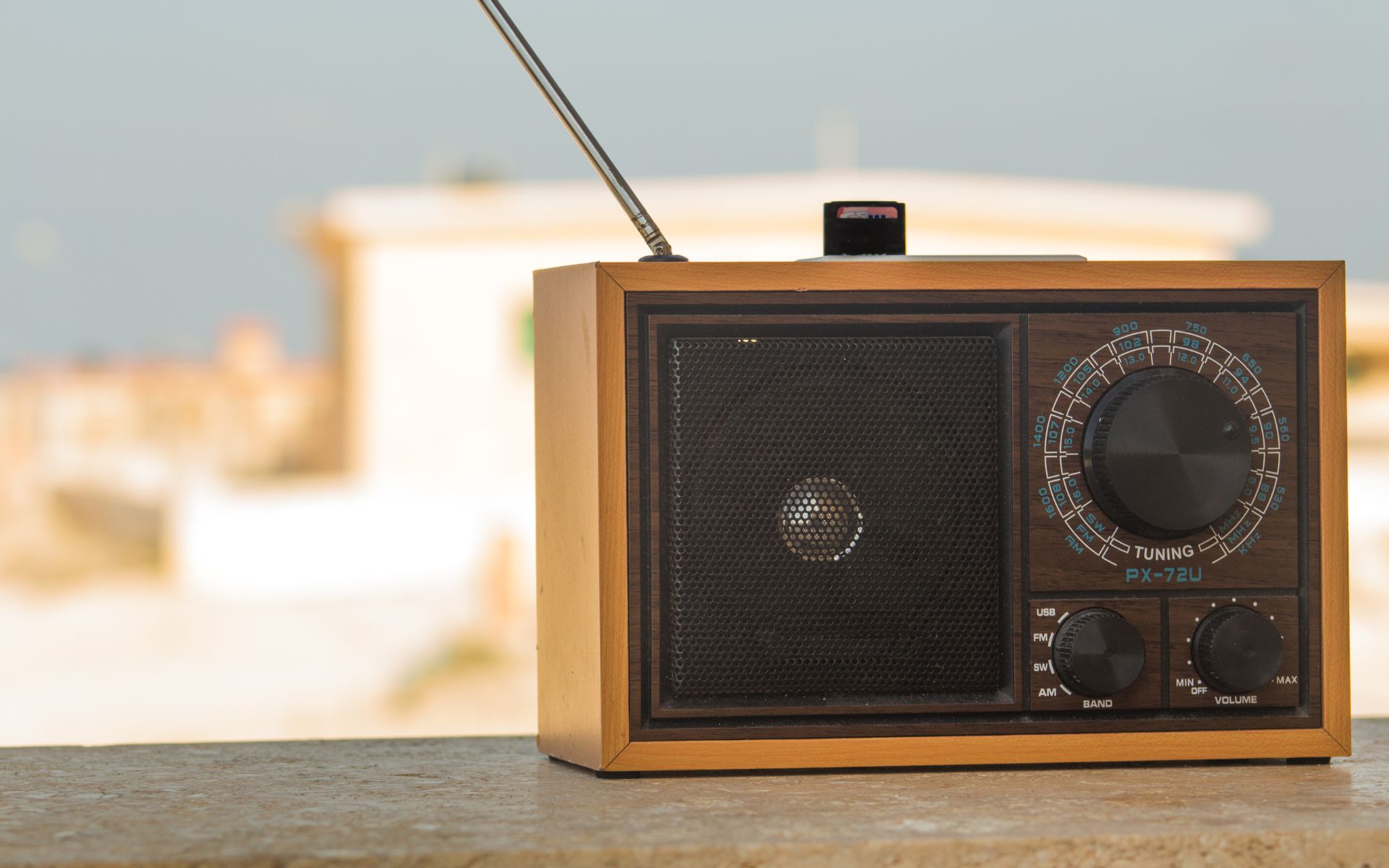 Imagen de una radio sobre un balcón con un paisaje de ciudad lluvioso de fondo